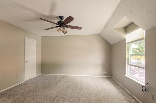 interior space featuring ceiling fan, vaulted ceiling, plenty of natural light, and carpet flooring