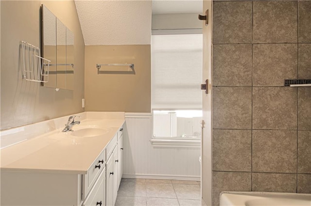 bathroom featuring vanity, vaulted ceiling, tile patterned floors, a textured ceiling, and a bathtub