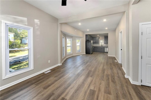 unfurnished living room featuring vaulted ceiling, dark hardwood / wood-style floors, and ceiling fan