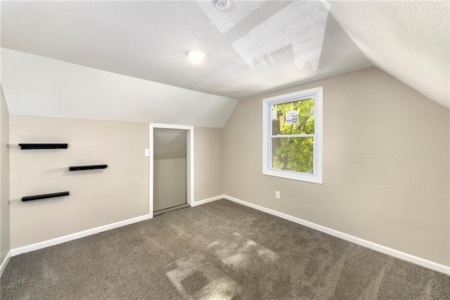 additional living space with a textured ceiling, lofted ceiling, and dark colored carpet