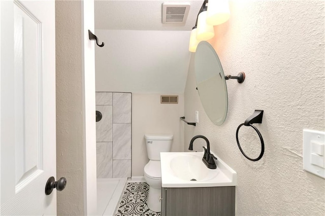 bathroom with toilet, vanity, and a tile shower