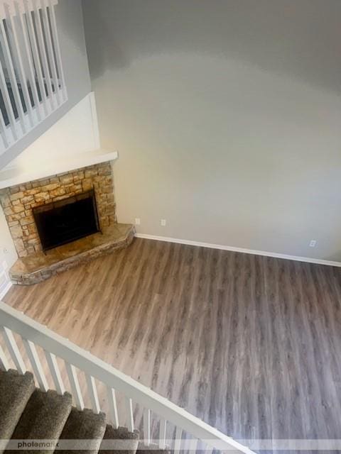 unfurnished living room with hardwood / wood-style floors and a stone fireplace