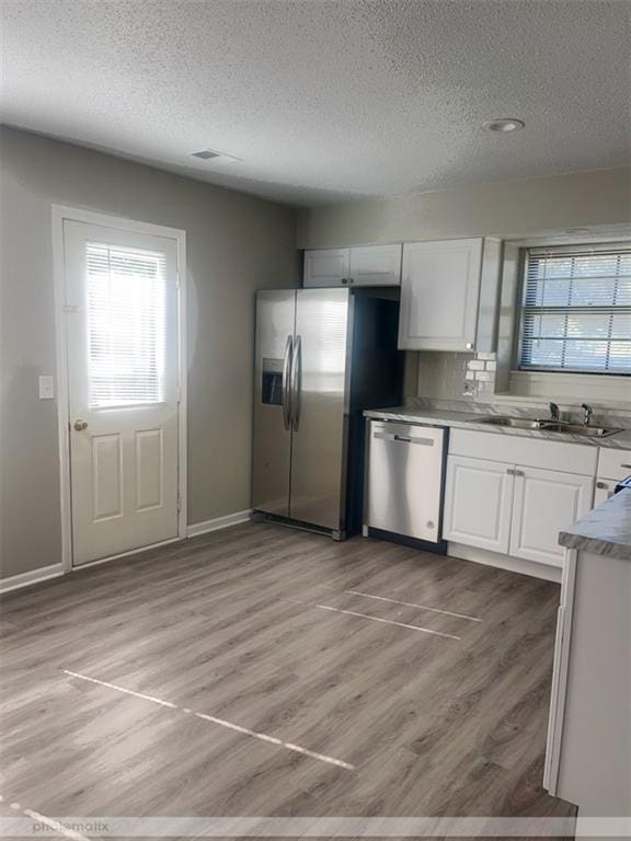 kitchen with white cabinets, sink, stainless steel appliances, and a wealth of natural light