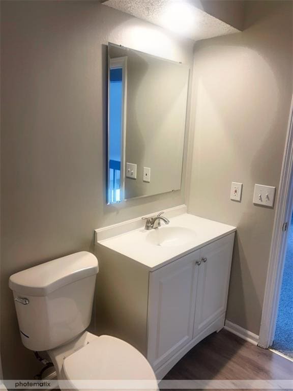 bathroom with vanity, wood-type flooring, a textured ceiling, and toilet