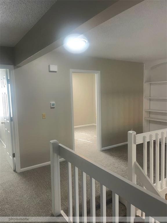 hall featuring carpet flooring and a textured ceiling