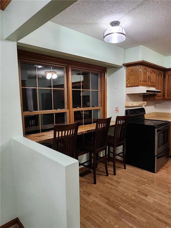 dining area with a textured ceiling and light hardwood / wood-style flooring