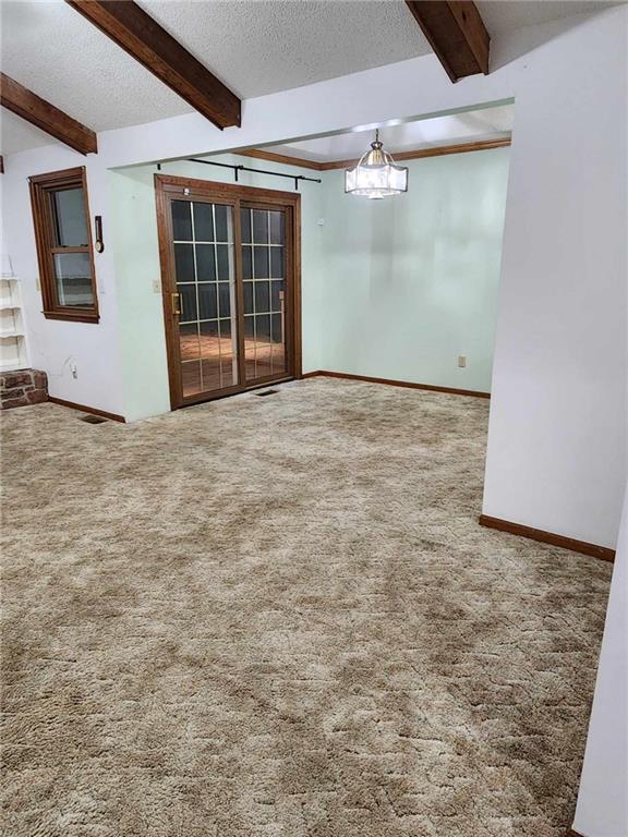 carpeted spare room with beamed ceiling and a textured ceiling