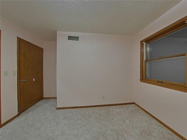 carpeted empty room featuring a textured ceiling