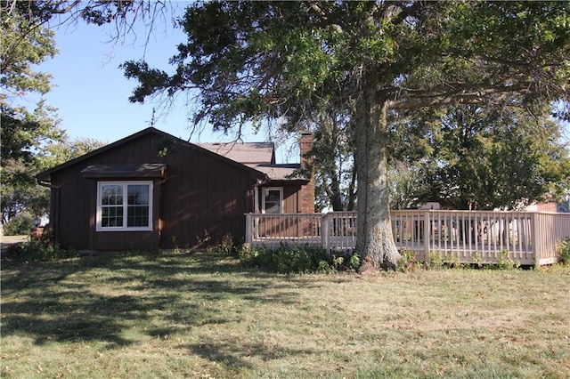 view of home's exterior with a lawn, a chimney, and a wooden deck