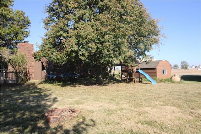 view of yard with a playground, a fire pit, and a trampoline