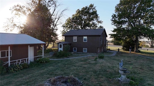 back of house featuring a storage unit, an outdoor structure, and a yard