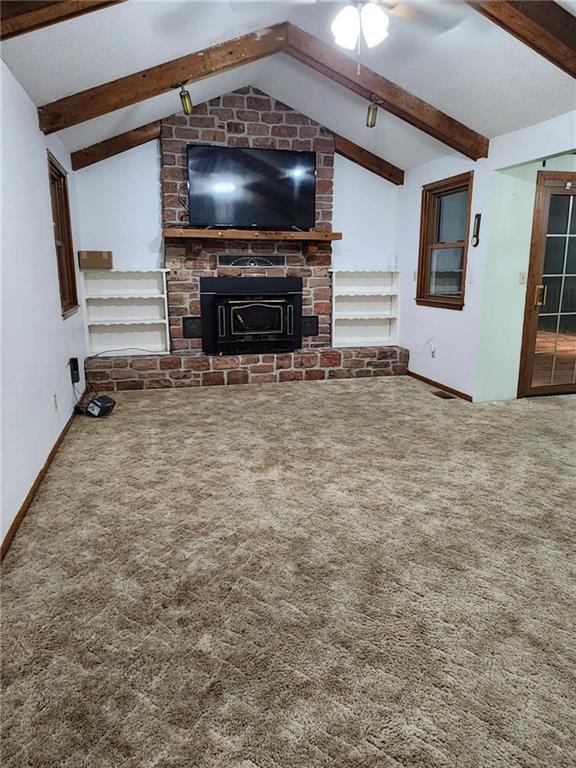 living area featuring baseboards, a ceiling fan, vaulted ceiling with beams, carpet floors, and a fireplace