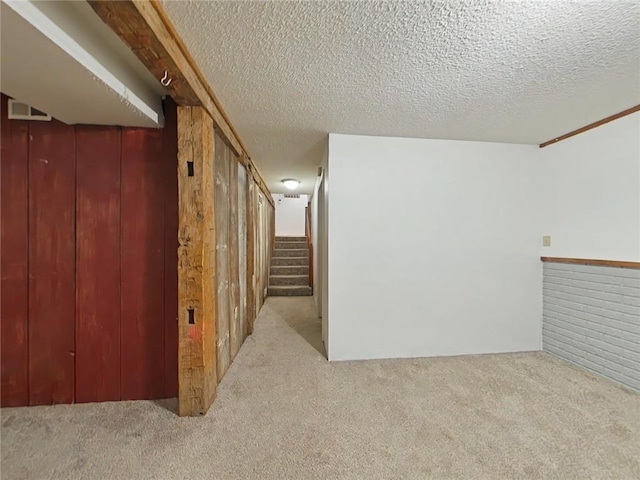 interior space with a textured ceiling, stairway, carpet, and wooden walls