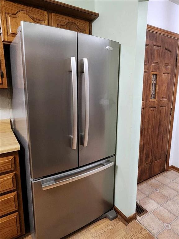interior details with baseboards, light countertops, freestanding refrigerator, and brown cabinets