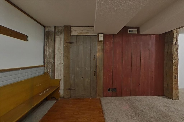 interior space featuring wooden walls, visible vents, and a textured ceiling