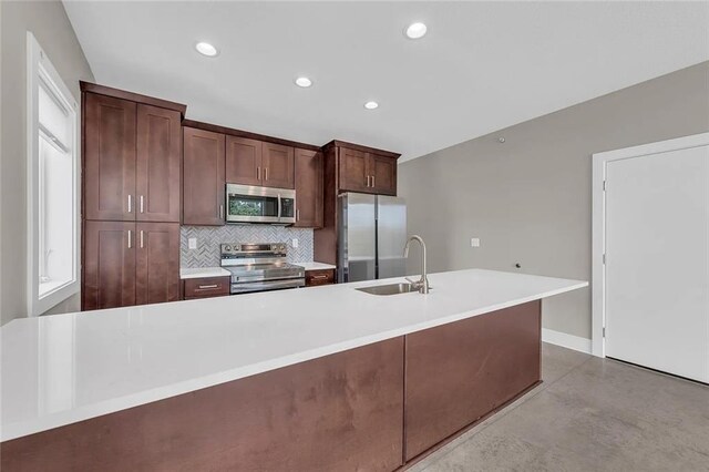 kitchen featuring tasteful backsplash, a center island with sink, appliances with stainless steel finishes, dark brown cabinetry, and sink