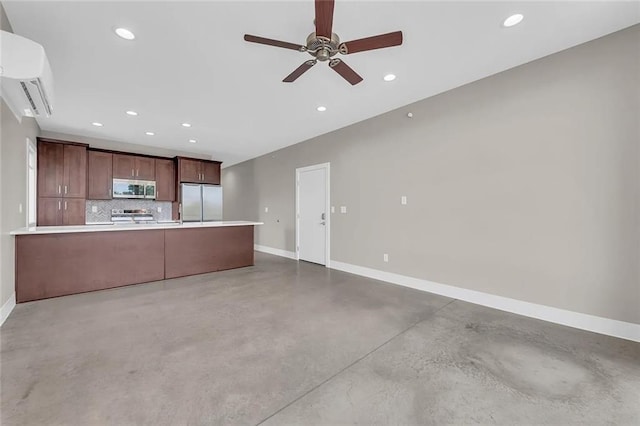 kitchen with an AC wall unit, concrete flooring, stainless steel appliances, backsplash, and kitchen peninsula