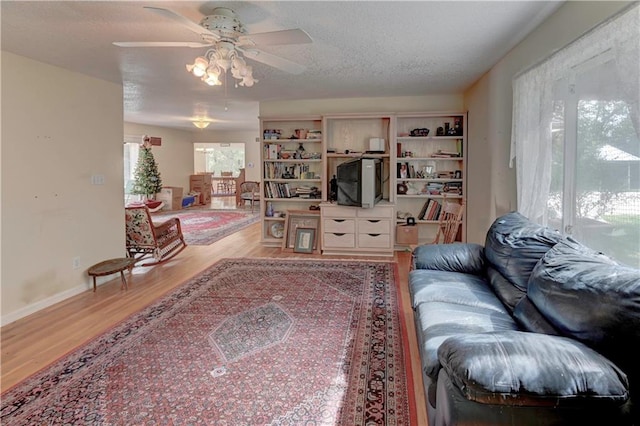 living room with ceiling fan, hardwood / wood-style flooring, and a textured ceiling