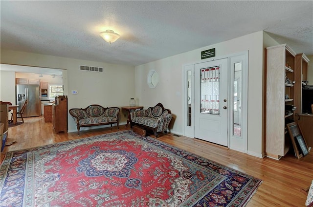 living room with plenty of natural light, a textured ceiling, and light wood-type flooring