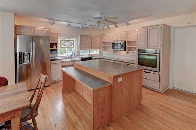 kitchen with appliances with stainless steel finishes, light wood-type flooring, a center island, ceiling fan, and track lighting