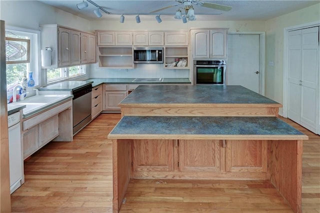 kitchen featuring a kitchen bar, a center island, ceiling fan, stainless steel appliances, and light hardwood / wood-style flooring