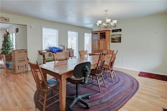 dining space with an inviting chandelier, a textured ceiling, and light hardwood / wood-style floors