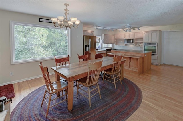 dining room featuring a textured ceiling, light hardwood / wood-style flooring, and ceiling fan with notable chandelier