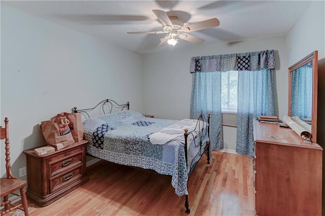 bedroom with a textured ceiling, light hardwood / wood-style floors, and ceiling fan