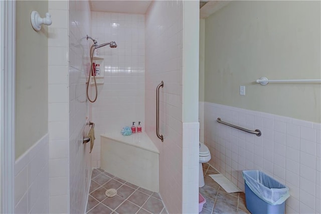 bathroom featuring tile walls, a tile shower, toilet, and tile patterned flooring