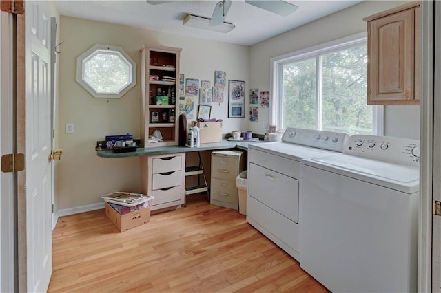 clothes washing area with ceiling fan, washing machine and clothes dryer, light wood-type flooring, and cabinets