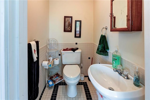 bathroom with toilet, sink, tile walls, and tile patterned flooring