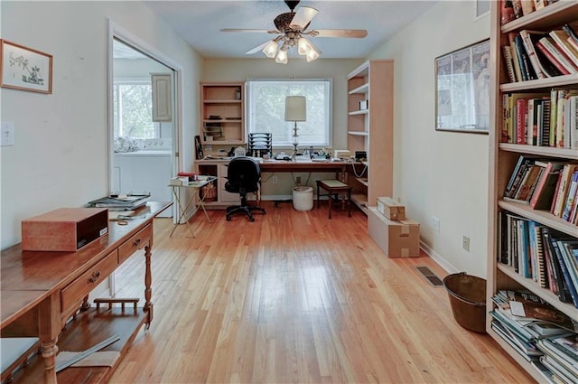 home office with built in desk, light hardwood / wood-style floors, and ceiling fan