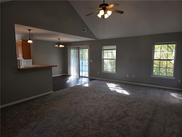 unfurnished living room with high vaulted ceiling, dark carpet, and ceiling fan with notable chandelier