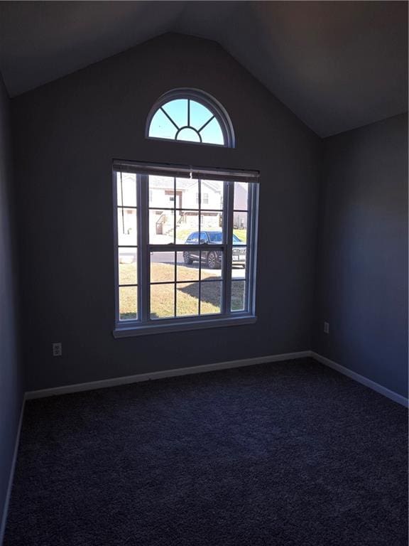 empty room featuring lofted ceiling and dark colored carpet