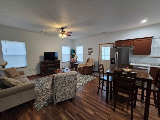 living room with a textured ceiling, dark hardwood / wood-style floors, and ceiling fan