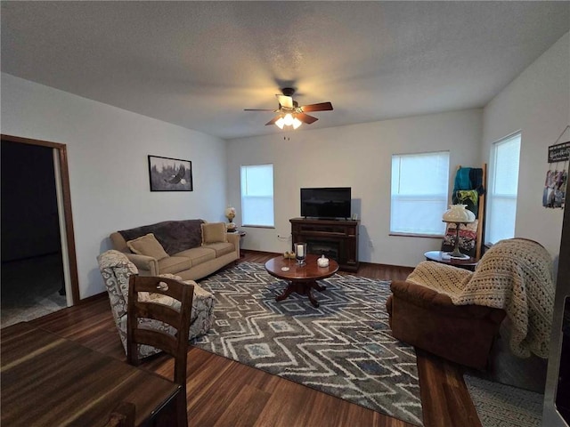 living room with ceiling fan, a textured ceiling, and dark hardwood / wood-style flooring