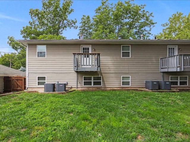 back of property with a balcony, cooling unit, and a lawn