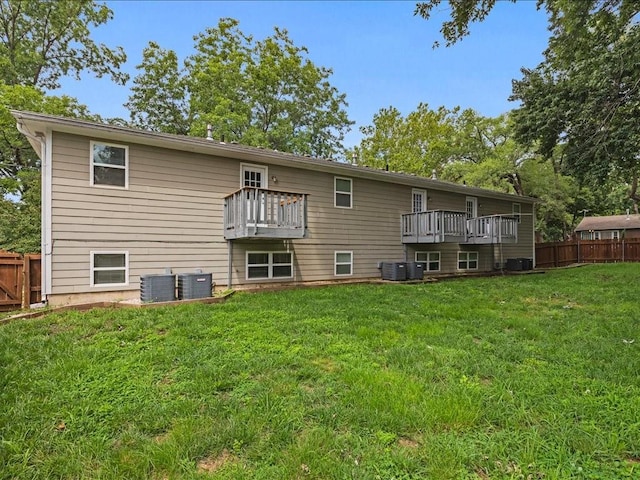 rear view of property with a yard, cooling unit, and a balcony