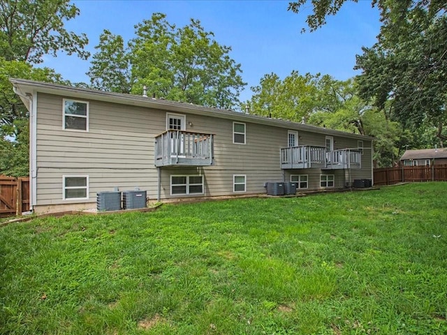 back of house featuring central air condition unit, a lawn, and a balcony