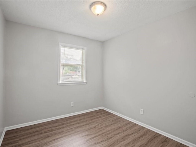 empty room with a textured ceiling and hardwood / wood-style flooring