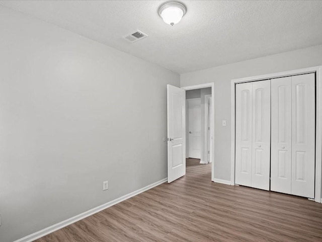 unfurnished bedroom featuring a closet, a textured ceiling, and hardwood / wood-style flooring