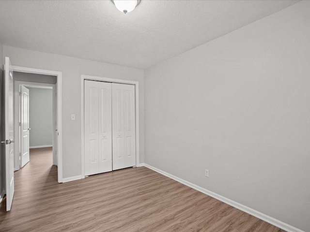 unfurnished bedroom with a closet, a textured ceiling, and light wood-type flooring