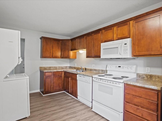 kitchen featuring washer / dryer, sink, light hardwood / wood-style flooring, and white appliances