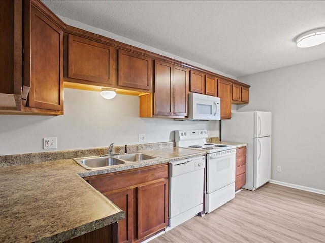 kitchen with a textured ceiling, sink, light wood-type flooring, and white appliances