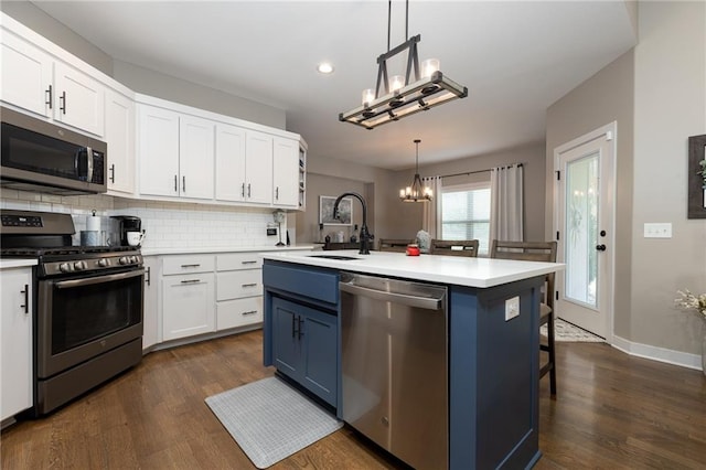 kitchen featuring appliances with stainless steel finishes, white cabinetry, a kitchen island with sink, blue cabinetry, and decorative light fixtures