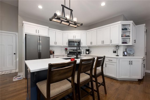 kitchen with white cabinets, tasteful backsplash, hanging light fixtures, dark hardwood / wood-style flooring, and stainless steel appliances