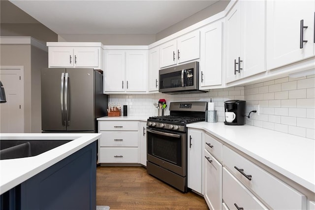 kitchen with dark wood-type flooring, backsplash, appliances with stainless steel finishes, and white cabinets