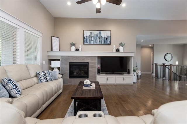 living room with a tiled fireplace, dark hardwood / wood-style floors, and ceiling fan