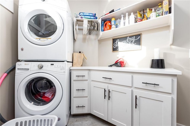 clothes washing area with cabinets and stacked washer and dryer