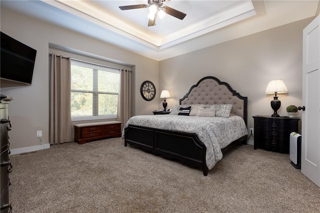 bedroom with a raised ceiling, carpet floors, and ceiling fan